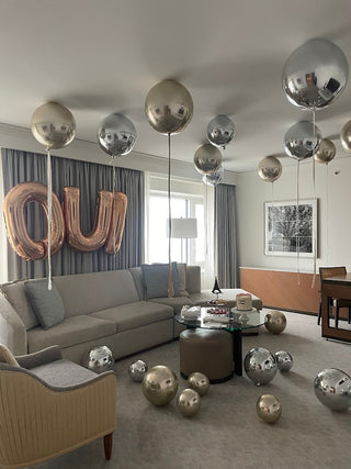 Luxury birthday balloon setup inside a Chicago high-rise hotel room overlooking the skyline.