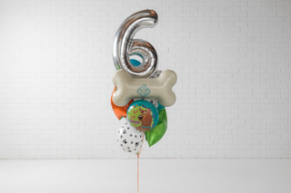 A Scooby Doo themed helium bouquet featuring a large bone-shaped balloon, a foil number 6, and character-themed balloons in a room.