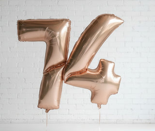 A large gold helium balloon in the shape of the number 7 with a reflective surface, displayed against a door backdrop.