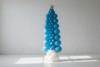 Balloon arch with blue and white balloons in front of a snowy landscape