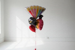 A colorful balloon bouquet with a 'GRADUATION' lettering, consisting of various shapes and colors of balloons, attached to a string.