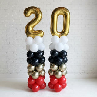 A multicolored balloon column featuring a spiral design with a mix of large and small balloons, including metallic and plain styles, set against a white background.