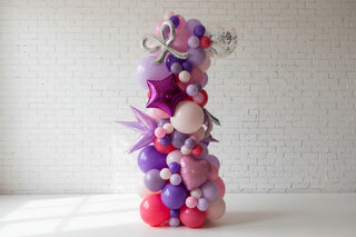 Colorful balloon arrangement with a silver bow and star-shaped balloon on a light background
