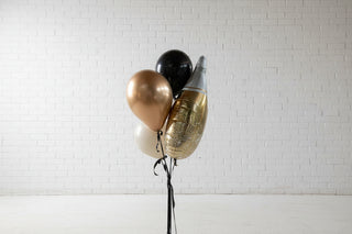 Decorative balloons in gold, black, and white against a white paneled wall.