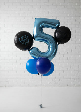 A helium bouquet featuring inflatable balloons shaped as a number '5' and superhero symbols in blue and black colors against a wall.