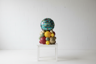 Colorful balloon arrangement with a 'Happy Thanksgiving' balloon on a table.