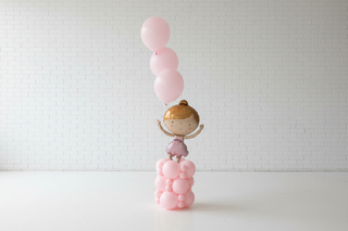 Decorative setup with balloons and a small figure in an indoor setting