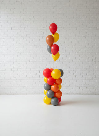 A column-shaped balloon display with a variety of colors including red, yellow, and gray, arranged in a indoor setting.