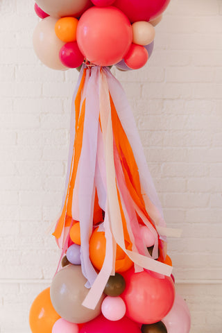 Decorative arrangement of balloons and ribbons against a light background