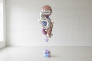 Gold number 5 balloon with decorative elements in a room setting.