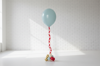 A helium balloon with a ticket tail attached, primarily in red and white colors, against a light-colored wall.