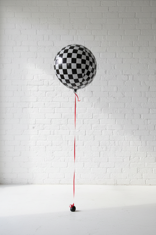 A large balloon with a checkered pattern released from a red string, resembling a whimsical decoration for a party.