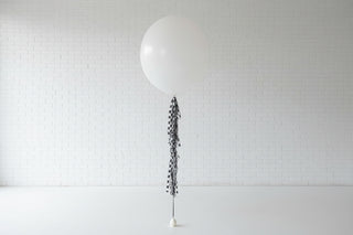 a white jumbo balloon with racecar checkers on the ribbon