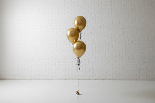 Gold balloons hanging in front of a white wall