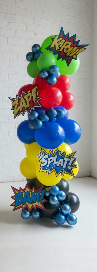 A colorful balloon column decoration featuring characters resembling superhero logos with 'Kapow!' and 'Splat!' text decorations.