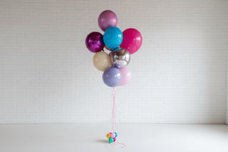 Bouquet of colorful balloons against a textured wall.