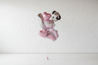 Bouquet of balloons with dog-themed designs against a brick wall.