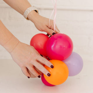 Colorful balloons held by a person with a neutral background