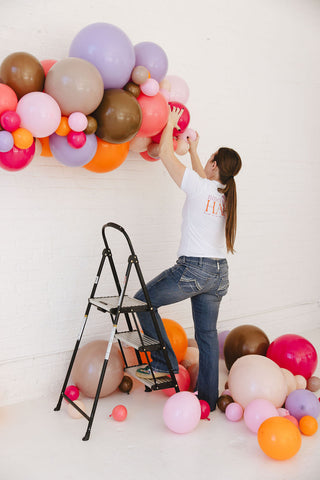 Founder of 99 Haus Balloons and Decor handing a balloon garland.