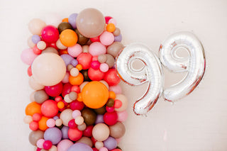 Colorful balloon arch with a silver number 99 on a white background