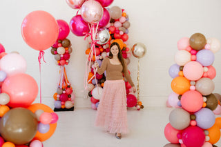 Founder of 99 Haus Balloons walking towards camera surrounded by colorful balloon columns
