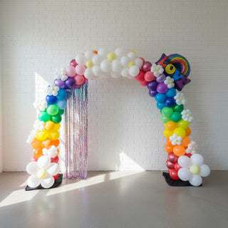 A balloon arch featuring a collection of latex and foil balloons, arranged organically in an indoor setting. 