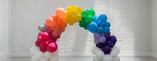 A balloon arch featuring a collection of latex and foil balloons, arranged organically in an indoor setting. 