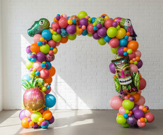 A balloon arch featuring a collection of latex and foil balloons, arranged organically in an indoor setting. 