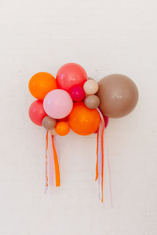 Colorful balloon arrangement with ribbons on a light background