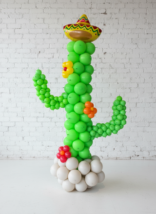 A balloon decoration designed to resemble a cactus with a party hat and decorative flowers.