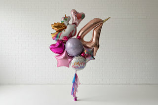 Colorful birthday balloons with a unicorn design against a white wall.