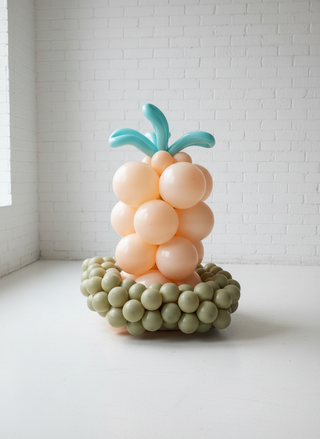 A balloon decoration resembling a carrot with a green base and beige carrots, topped with a blue handle.