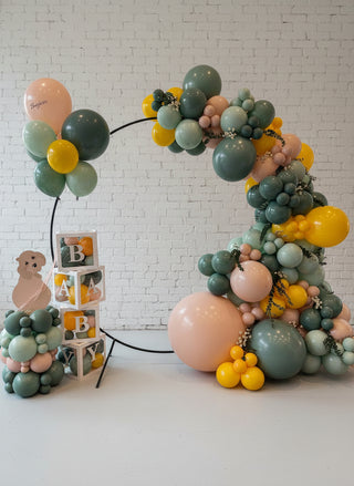 A balloon hoop backdrop featuring a variety of balloons in different shapes and colors, with a small figurine and decorative elements.