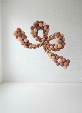 A large decorative bow made from small balloons mounted on a white wall. 