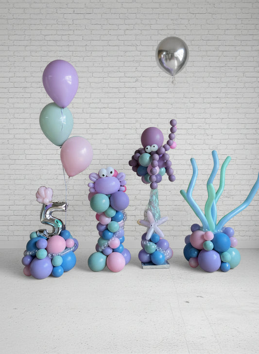 A set of balloon centerpiece decorations for a under-the-sea themed party, including round multicolored balloons, an octopus figure, and seaweed shapes.