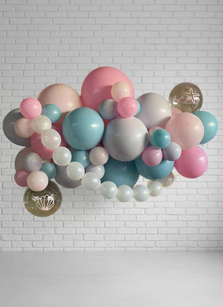 A garland of round balloons in shades of blue, pink, gold, and white, arranged to form a playful sea themed pouf. 