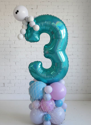 A balloon column decoration featuring a large number 3 with a deep sea theme, including blue, green, and purple colors, and sea creature balloons such as an octopus.
