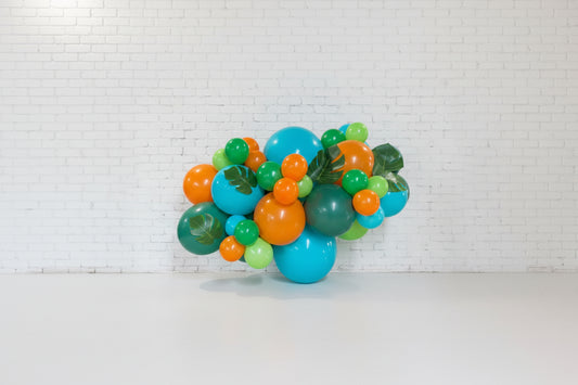 A garland decoration featuring a cluster of balloons in shades of blue, orange, and green, with some balloons designed to look like dinosaur eggs or shaped like leaves.