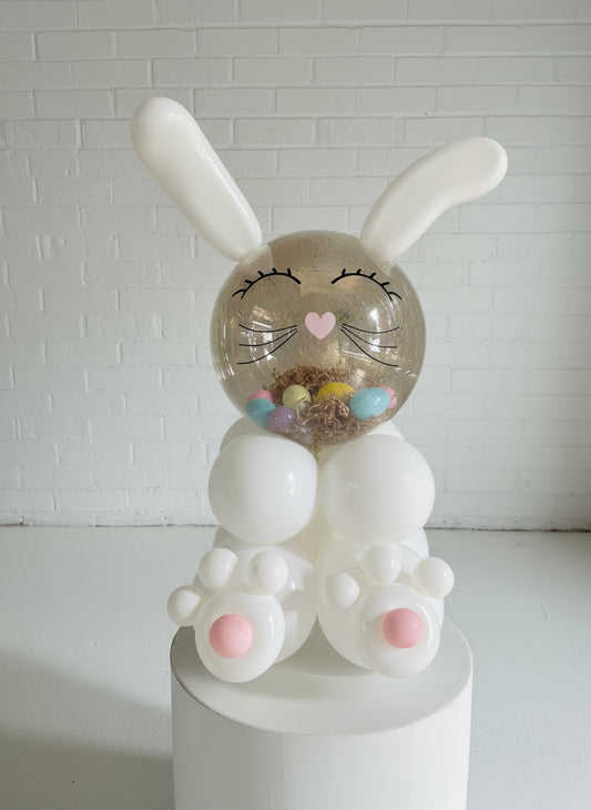 A balloon gift in the shape of an Easter bunny with a face, long ears, and feet, filled with small non-candy surprises.
