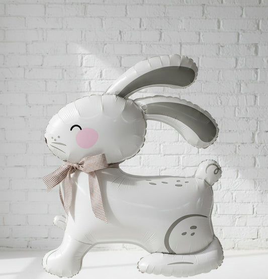 A white, air-filled balloon in the shape of an Easter bunny with a decorative bow.