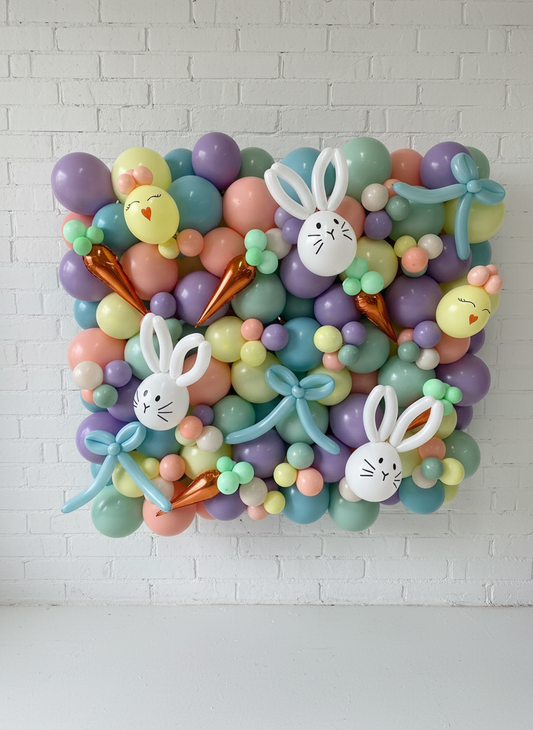 A wall decoration featuring an array of colorful balloons arranged in the shape of a square frame with bunny faces and Easter-themed patterns.