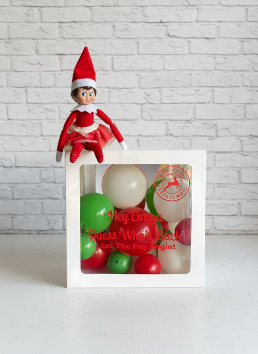 A white mailbox-shaped balloon display with a red and white striped top resembling a Christmas hat, set against a plain background.