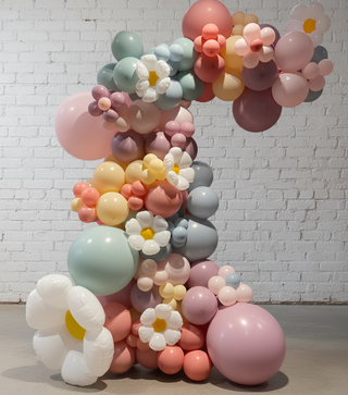 A decorative balloon arch featuring a variety of colors and designs resembling flowers, set against a white background.