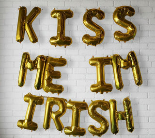 A set of gold-colored balloon letters spelling out the phrase 'KISS ME IRISH'.