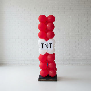 A balloon column decoration with a 'TNT' label, predominantly red with white balloons, standing upright on a base.