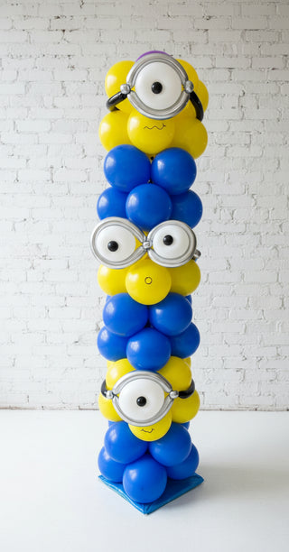 A balloon column tower featuring blue and yellow balloons with eyes resembling a minion character from the movie 'Despicable Me'.