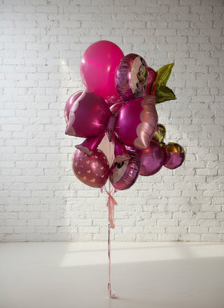 A helium bouquet featuring round pink balloons and shapes of Minnie and Mickey Mouse, tied together with a ribbon against a plain background.