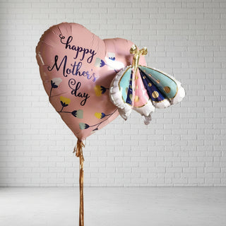 A pink heart-shaped helium balloon with 'Happy Mother's Day' printed on it, adorned with a decorative bow.
