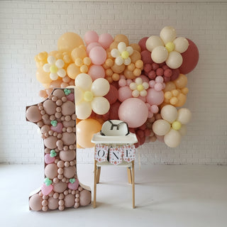 a floral balloon wall paired with a decorative number one made from balloons