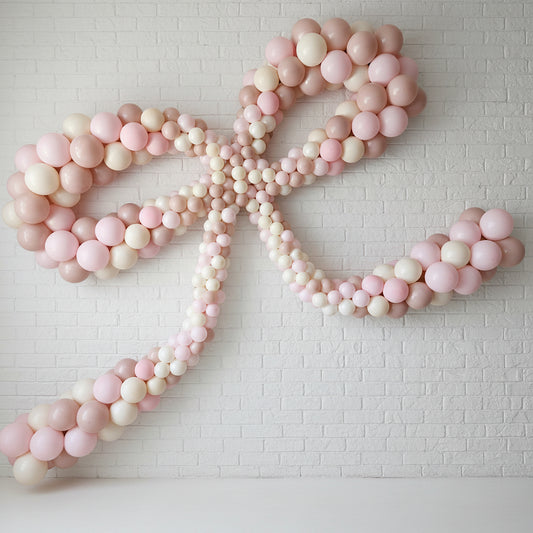 A pink balloon bow decoration displayed on a wall, creating a decorative element for an event.